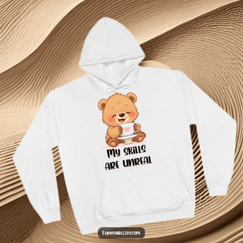 Funny hoodie featuring a giggling grizzly bear cub attempting to balance a teacup on its head, blending coziness with comical effort.