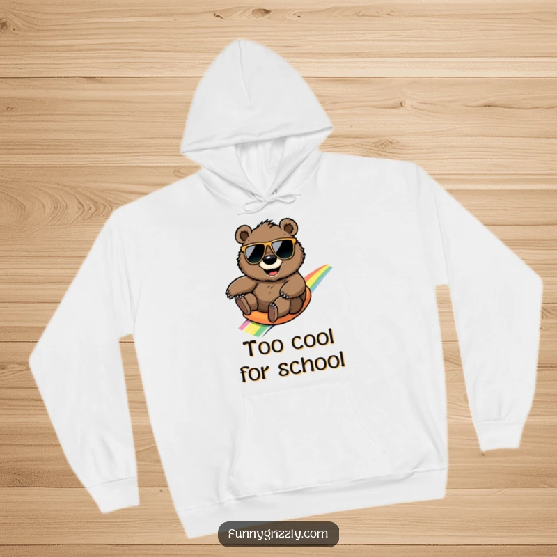 Funny grizzly bear in oversized sunglasses sliding down a rainbow, featured on a cozy and humorous hoodie.