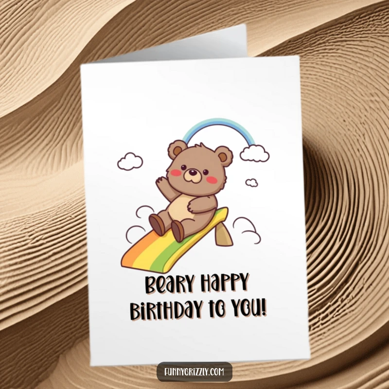 Funny Free Printable Birthday Card: Grizzly bear gleefully slides down a vibrant rainbow, spreading joy and birthday cheer. A unique downloadable gift.
